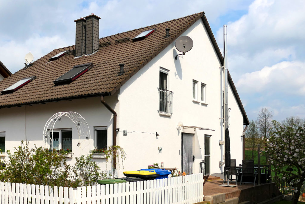 Ein weißes Haus mit einem weißen Zaun zum Verkauf.
